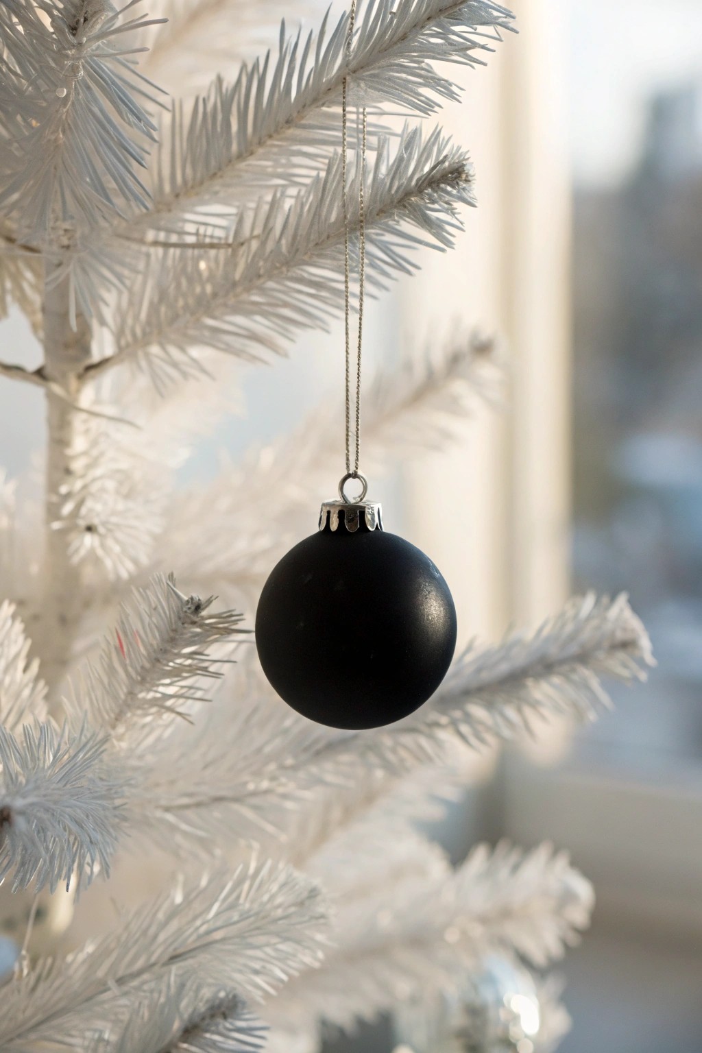 Chic contrast: a matte black ornament makes a bold statement on a snowy white tree.